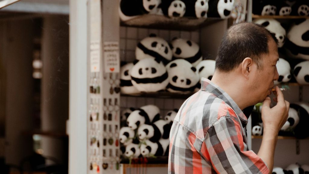 man in red white and blue plaid dress shirt standing near white wooden cabinet