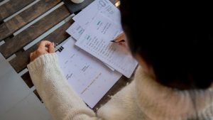 person in white long sleeve shirt writing on white paper