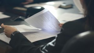 a woman sitting at a table reading a paper