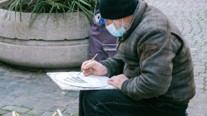 man in gray jacket and black knit cap reading book