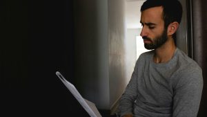 man in gray crew neck shirt holding white printer paper