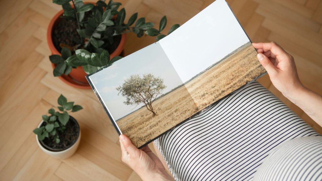 a person holding a book with a picture of a tree on it