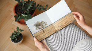 a person holding a book with a picture of a tree on it