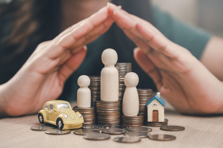 Family financial plan. Finance investment on real estate. Family invest in insurance save plan. A woman is holding her hand over a pile of coins and a toy car.
