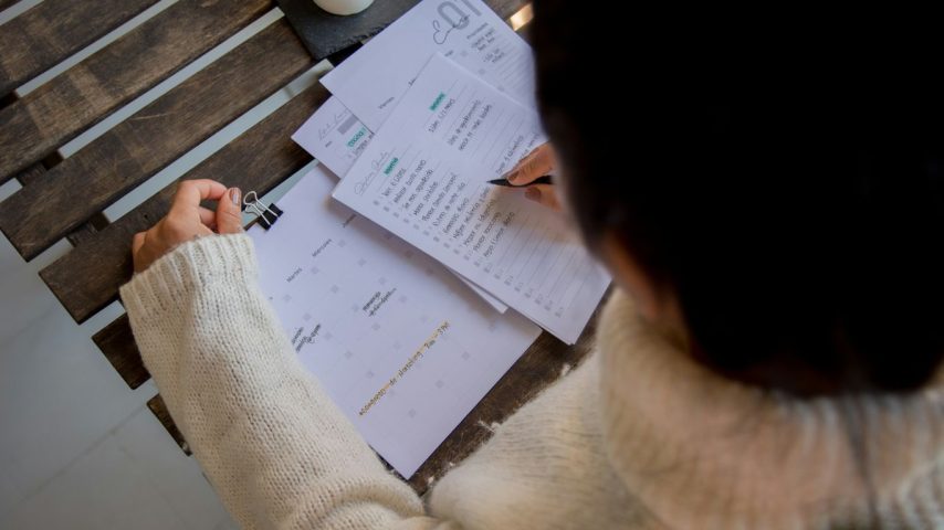 person in white long sleeve shirt writing on white paper