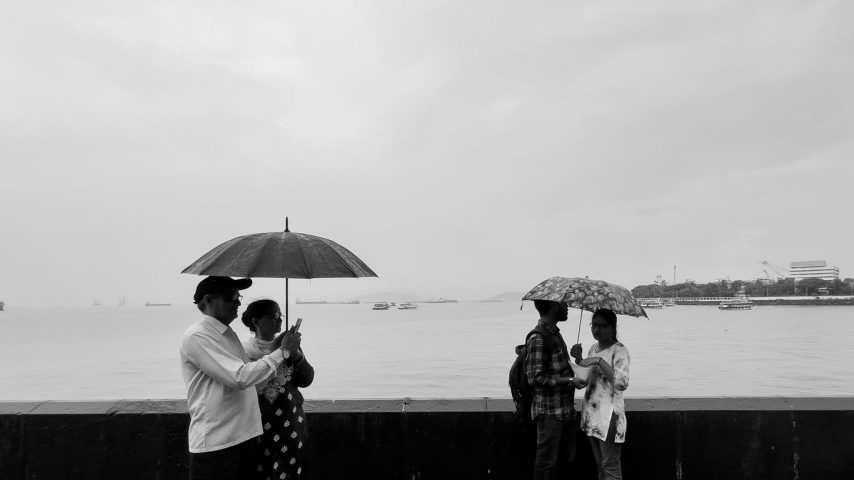 A group of people standing next to each other under an umbrella