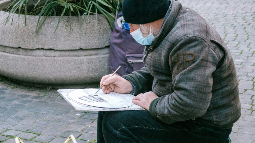 man in gray jacket and black knit cap reading book