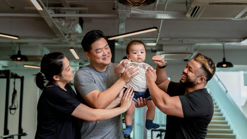 Family and trainer celebrate baby in the gym.