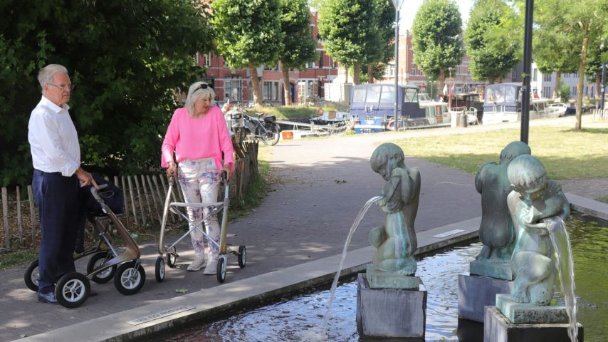 Elderly couple with walkers by a fountain