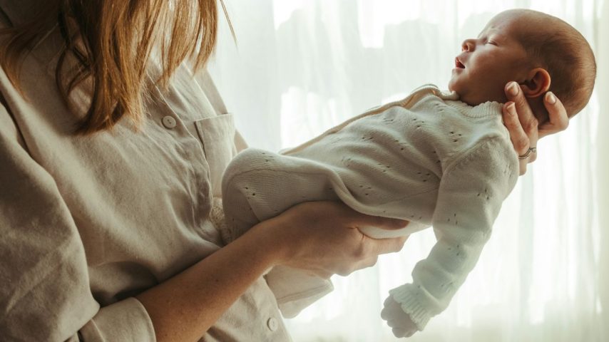 Mother holding her newborn baby near a window