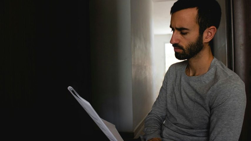 man in gray crew neck shirt holding white printer paper