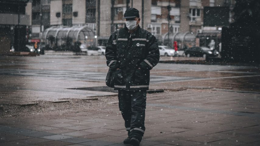 man in black coat standing on sidewalk during daytime