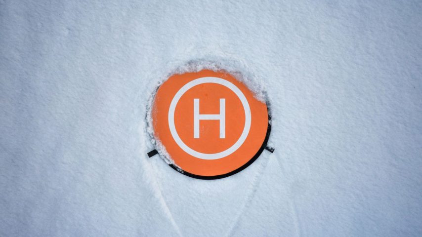 an orange circle with a white h on it in the snow