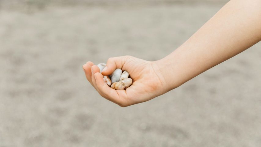 A child holds small, smooth stones in their hand.