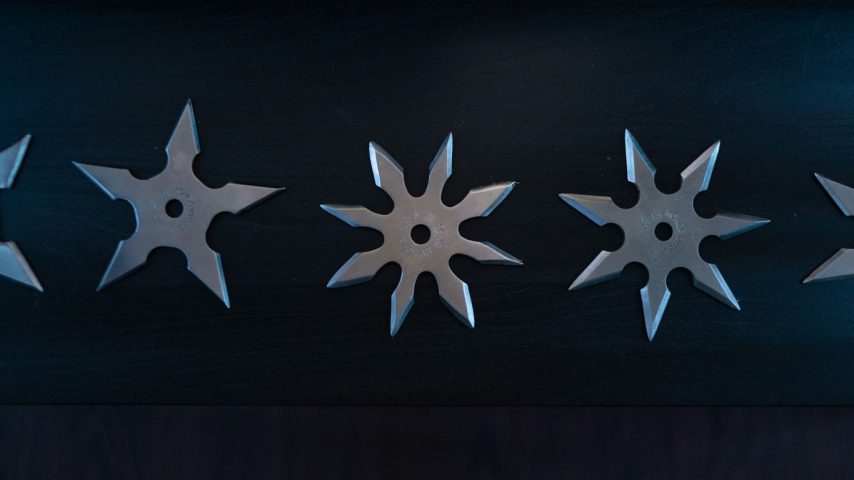grey throwing knives on black surface