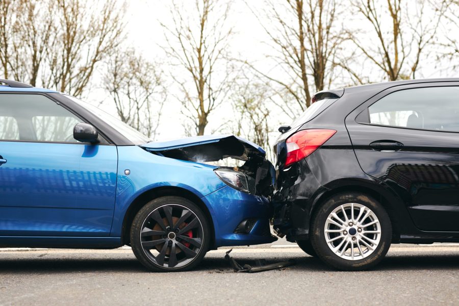 Two cars involved in traffic accident on side of the road with damage to bonnet and fender